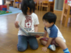 年長児が年少児に絵本を読んであげています